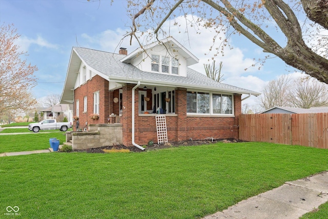 bungalow-style home featuring a front yard, covered porch, a chimney, fence, and brick siding