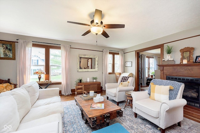living room with a ceiling fan, wood finished floors, and a glass covered fireplace