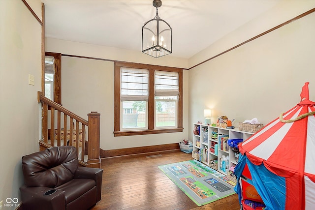 recreation room with wood-type flooring, baseboards, and an inviting chandelier