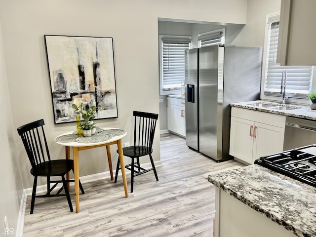 4205 Rookwood Ave, Indianapolis, IN 46208 - kitchen with light stone counters, white cabinetry, appliances with stainless steel finishes, light wood finished floors, and a sink