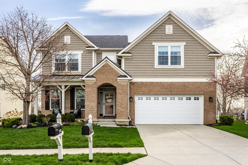 view of front of property featuring driveway, a front yard, a garage, and brick siding