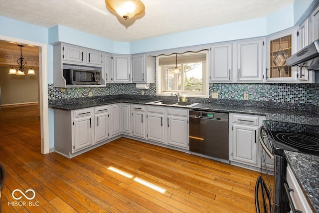 kitchen featuring an inviting chandelier, a sink, stainless steel appliances, decorative backsplash, and light wood-style flooring