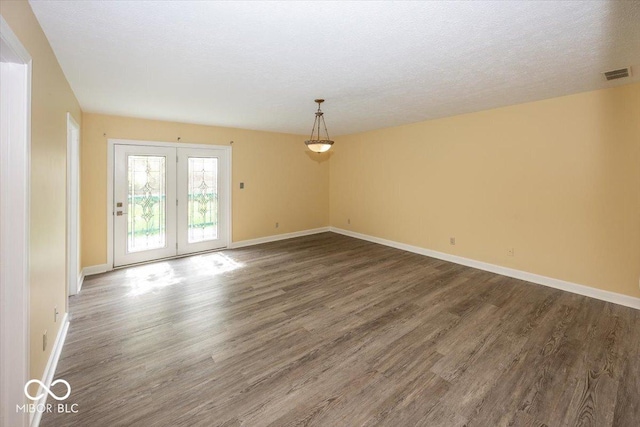 empty room with wood finished floors, visible vents, french doors, and baseboards