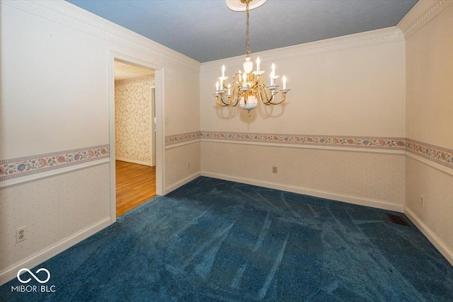 spare room featuring an inviting chandelier, wallpapered walls, dark colored carpet, and visible vents