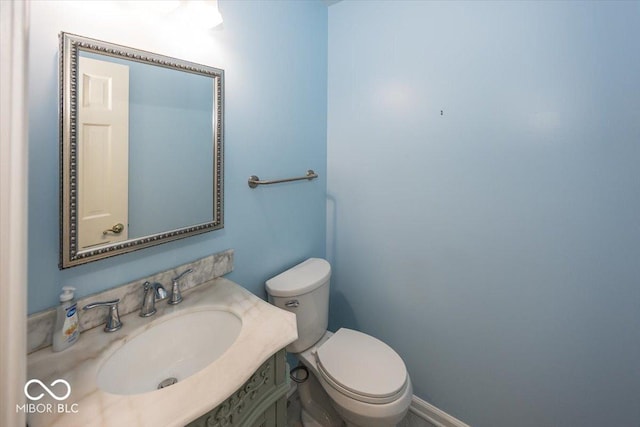 bathroom featuring toilet, vanity, and baseboards