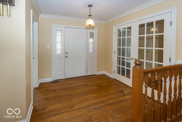 foyer featuring crown molding, visible vents, hardwood / wood-style flooring, and baseboards