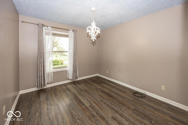 unfurnished room featuring dark wood-style floors, a textured ceiling, a notable chandelier, and baseboards