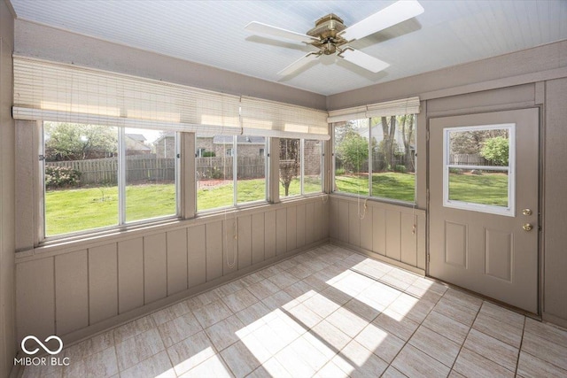 unfurnished sunroom featuring tile patterned floors, ceiling fan, and a healthy amount of sunlight