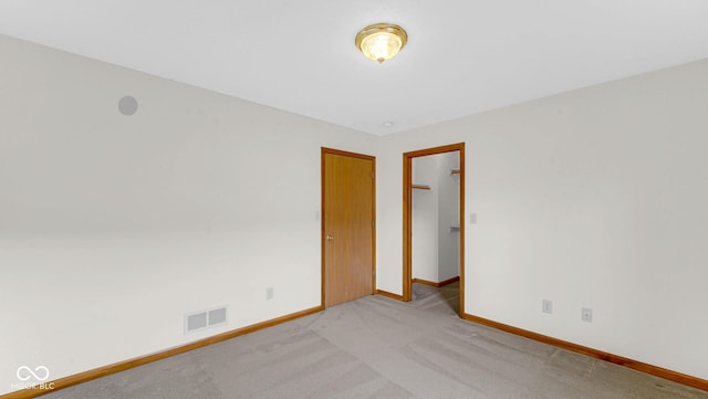 empty room with visible vents, baseboards, and light carpet