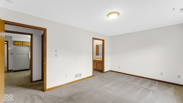 empty room featuring light carpet, baseboards, and visible vents