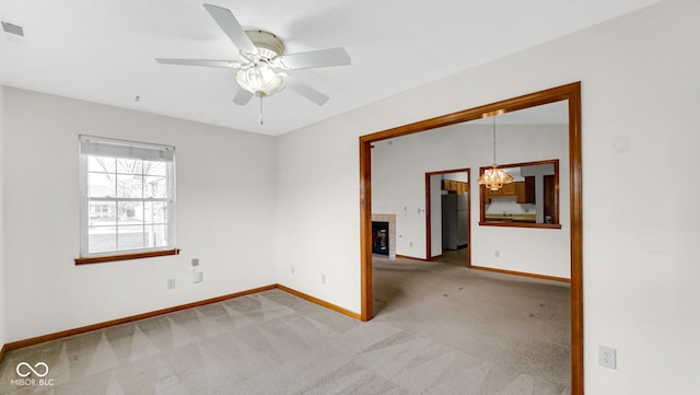 unfurnished room featuring ceiling fan with notable chandelier, light colored carpet, baseboards, and visible vents