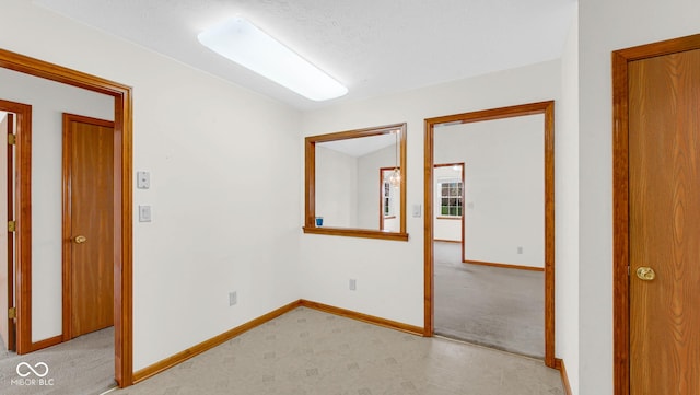 empty room featuring baseboards and light colored carpet