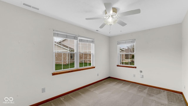 carpeted empty room with visible vents, baseboards, and a ceiling fan