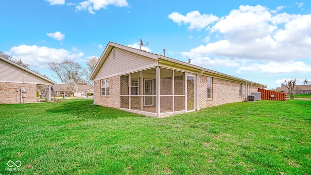 back of property with brick siding, a sunroom, a lawn, and central air condition unit
