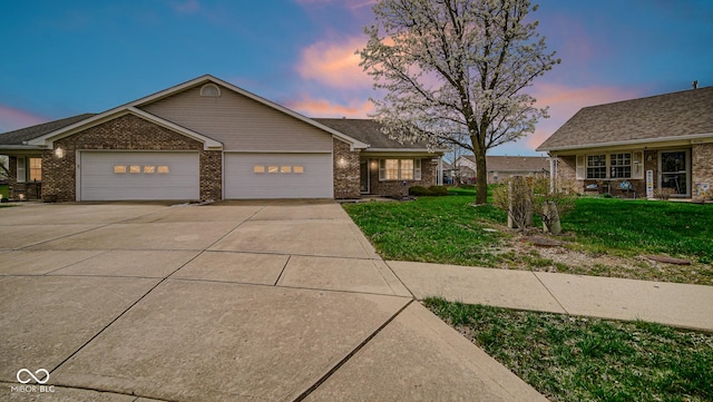 ranch-style home featuring a garage, brick siding, driveway, and a lawn