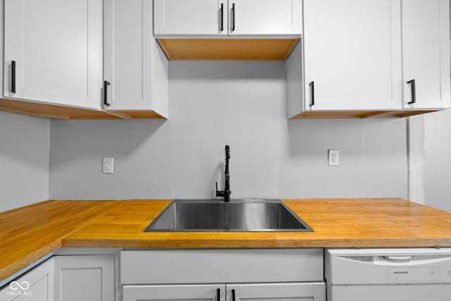 kitchen featuring a sink, butcher block countertops, white cabinetry, and dishwasher