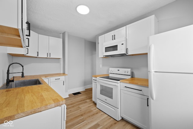 kitchen featuring white cabinets, a sink, white appliances, butcher block counters, and light wood finished floors