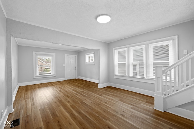 interior space featuring crown molding, baseboards, wood finished floors, and stairs