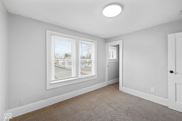 carpeted spare room featuring baseboards