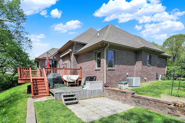 rear view of property with central air condition unit, brick siding, a patio area, and roof with shingles
