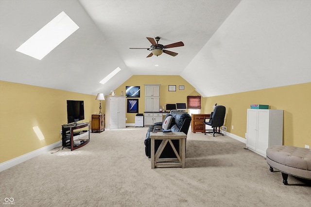 carpeted office space featuring ceiling fan, baseboards, and vaulted ceiling with skylight