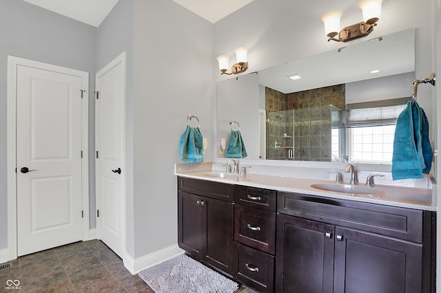 bathroom featuring baseboards, a sink, a tile shower, and double vanity