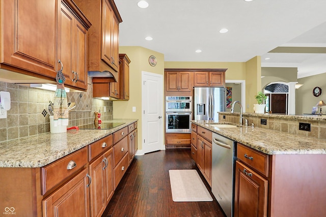 kitchen with light stone counters, a sink, decorative backsplash, and stainless steel appliances