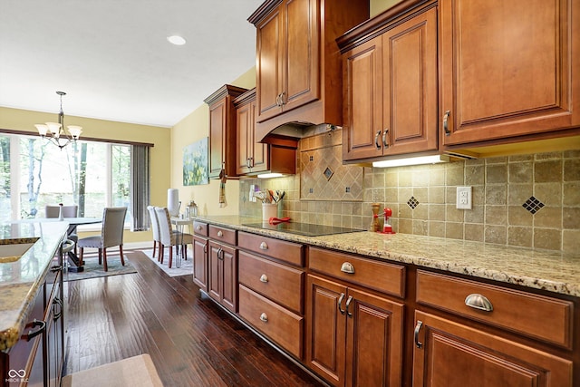 kitchen featuring backsplash, light stone countertops, baseboards, an inviting chandelier, and dark wood-type flooring