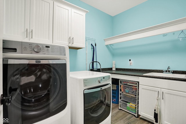 clothes washing area featuring washing machine and clothes dryer, cabinet space, a sink, and wood finished floors