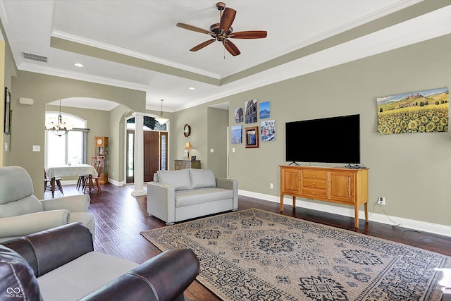 living room with arched walkways, ceiling fan with notable chandelier, baseboards, a tray ceiling, and dark wood-style floors