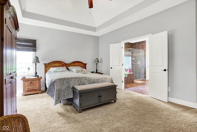 bedroom with baseboards, light colored carpet, ceiling fan, and ensuite bath