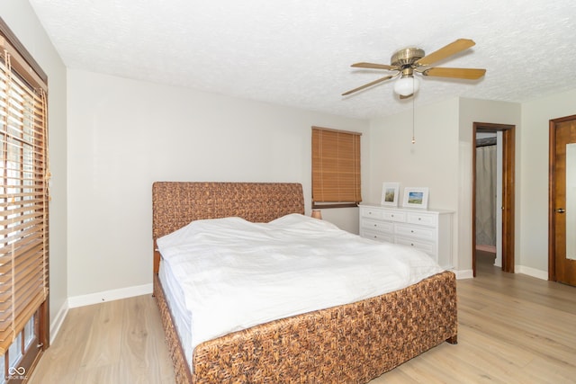 bedroom with baseboards, light wood finished floors, ceiling fan, and a textured ceiling