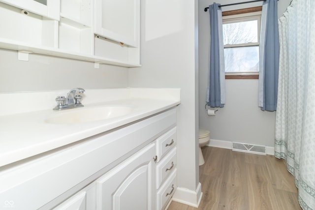 bathroom featuring visible vents, baseboards, toilet, vanity, and wood finished floors