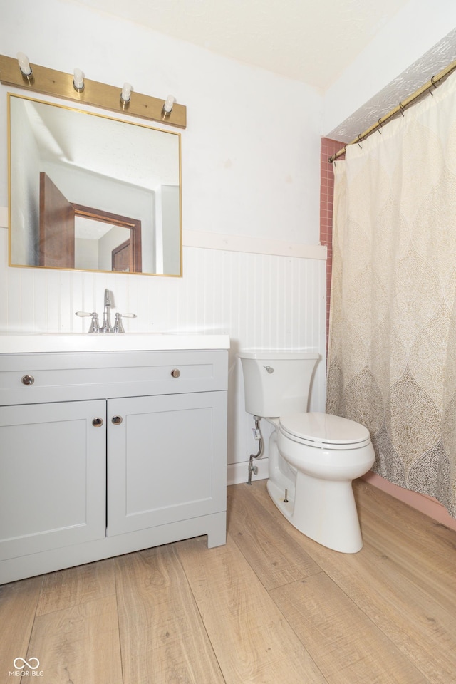 full bath with toilet, curtained shower, wood finished floors, and vanity