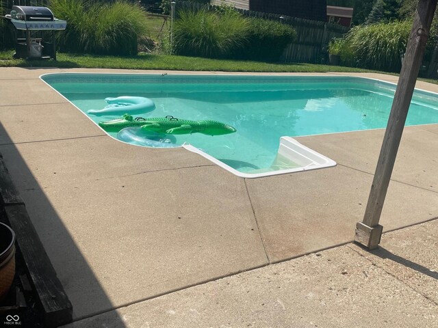 outdoor pool with fence, a grill, and a patio