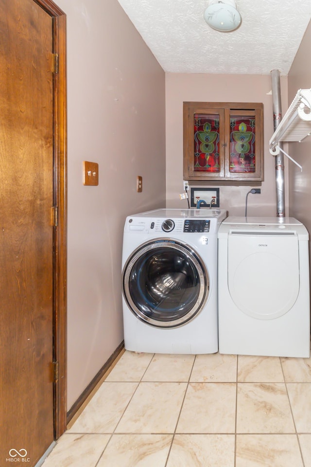 laundry room featuring separate washer and dryer, baseboards, tile patterned floors, a textured ceiling, and laundry area