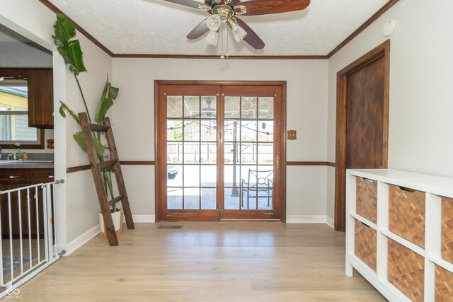 doorway to outside featuring light wood-style flooring, a textured ceiling, ornamental molding, and visible vents
