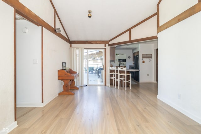interior space featuring light wood-type flooring, baseboards, and lofted ceiling