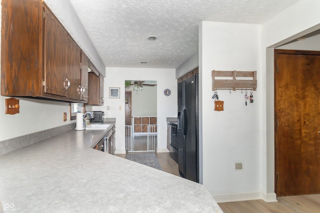 kitchen featuring baseboards, a textured ceiling, black fridge, a ceiling fan, and a sink