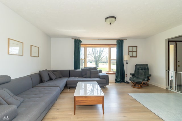 living room with baseboards, light wood-type flooring, and a textured ceiling