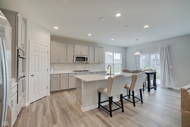 3799 Hoosier Down Dr, Bargersville, IN 46106 - kitchen with stainless steel appliances, a breakfast bar, a sink, light wood-style floors, and a center island with sink
