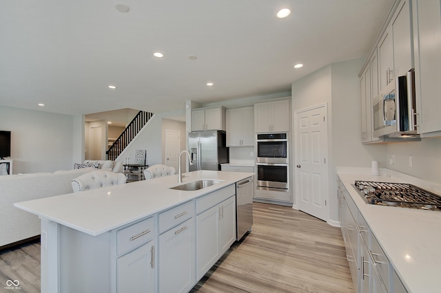 3799 Hoosier Down Dr, Bargersville, IN 46106 - kitchen with light countertops, a sink, light wood-style flooring, appliances with stainless steel finishes, and open floor plan
