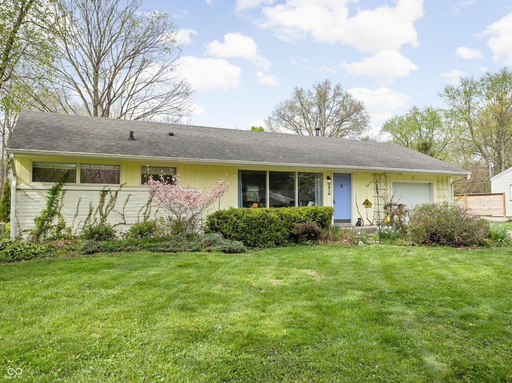 single story home featuring an attached garage and a front lawn