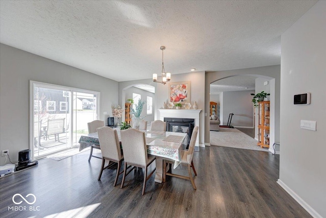 5839 Altar Bell Cir, Greenwood, IN 46143 - dining room featuring a textured ceiling, arched walkways, baseboards, a glass covered fireplace, and dark wood-type flooring
