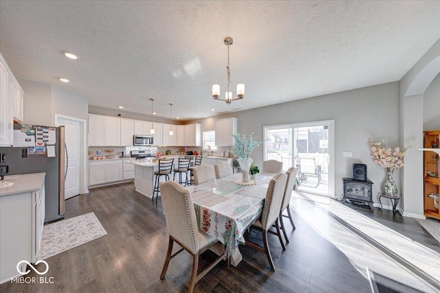 5839 Altar Bell Cir, Greenwood, IN 46143 - dining area featuring a textured ceiling, an inviting chandelier, dark wood-style floors, and a wood stove