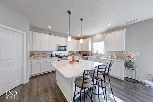 5839 Altar Bell Cir, Greenwood, IN 46143 - kitchen featuring dark wood-style flooring, appliances with stainless steel finishes, a center island, a sink, and white cabinetry