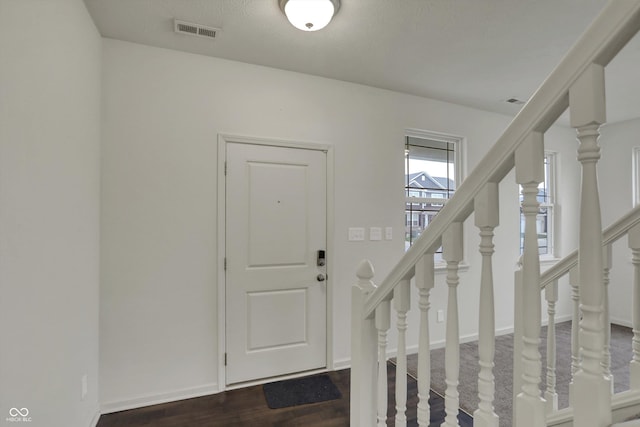 foyer featuring stairs, visible vents, dark wood-style flooring, and baseboards