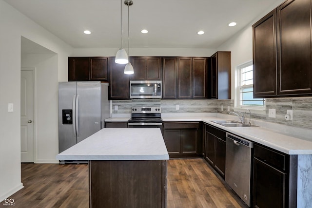 kitchen with appliances with stainless steel finishes, a sink, dark wood finished floors, and dark brown cabinetry