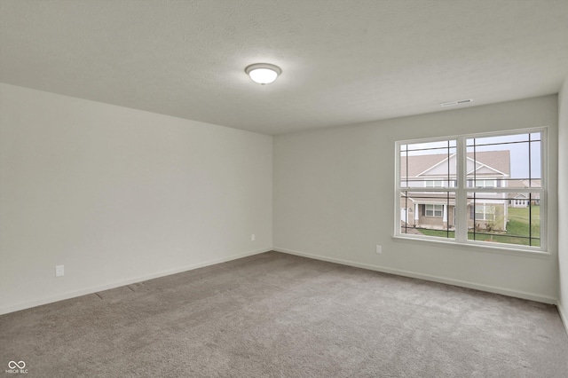 empty room featuring visible vents, baseboards, a textured ceiling, and carpet floors