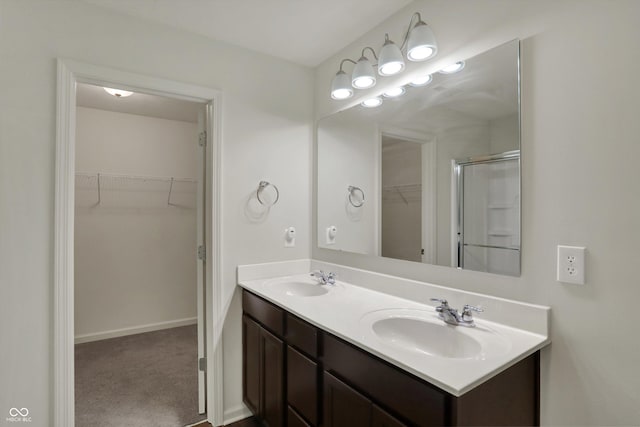 bathroom with a spacious closet, double vanity, a sink, and a shower with door